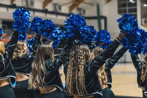 A Group Of Cheerleaders In Mid Performance Their Blue Pom Poms Waving