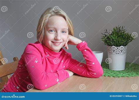 Schönes Blondes Mädchen Des Schulpflichtigen Alters Lächelnd Sitzend Am Tisch Stockbild Bild