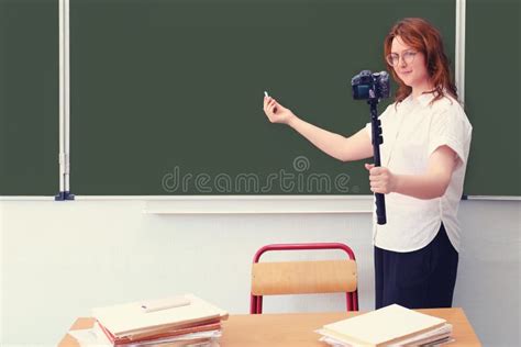 School Teacher Stands At The Blackboard And Conducts A Lesson On A