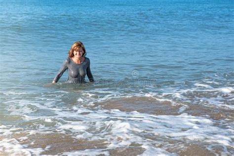 Woman Coming Out Of The Sea In A Wet Dress After A Swim At The Beach