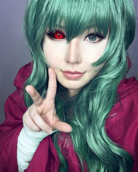 A Woman With Green Hair And Red Eyes Making The Peace Sign While