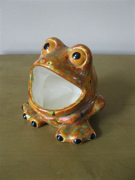 A Ceramic Frog Sitting On Top Of A Wooden Table