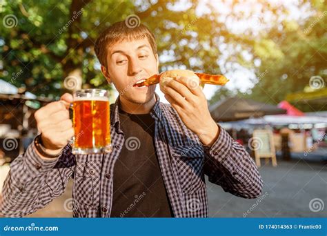 Man Drinking Beer At Outdoors Cafe And Eating Hot Dog Stock Image