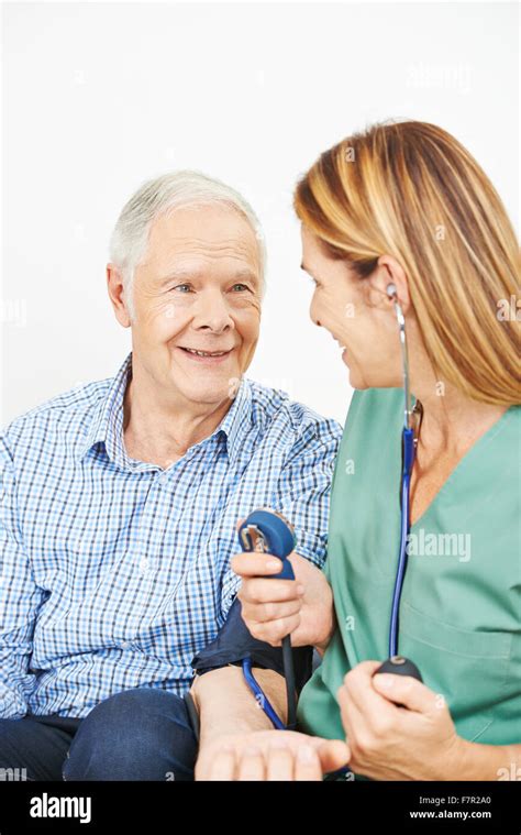 Nurse Doing Blood Pressure Monitoring For Senior Man At Home Stock