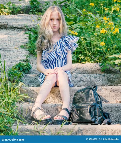 Young Beautiful Girl Sitting On The Stairs In The Park With Flower