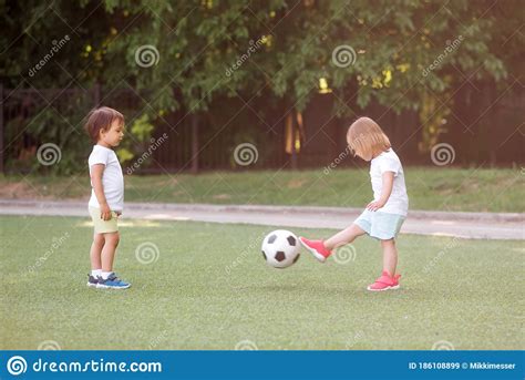 Toddler Children Boy And Girl Playing Soccer Together At Football