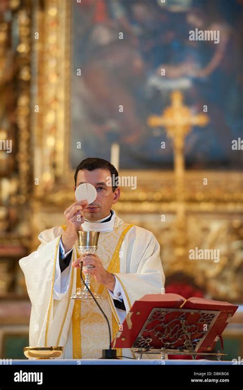 Priest Holding Host And Wine Chalice During Holy Communion While