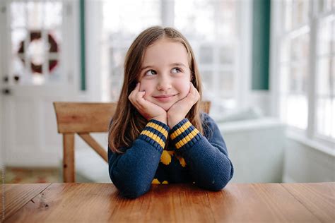 Ver Cute Young Girl Smiling At Table Del Colaborador De Stocksy