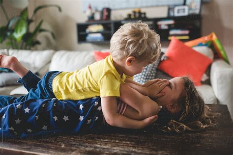 Siblings Hugging And Wrestling On Coffee Table By Stocksy Contributor