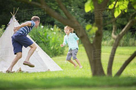Father Chasing Son Around Teepee In Backyard Stock Photo Dissolve