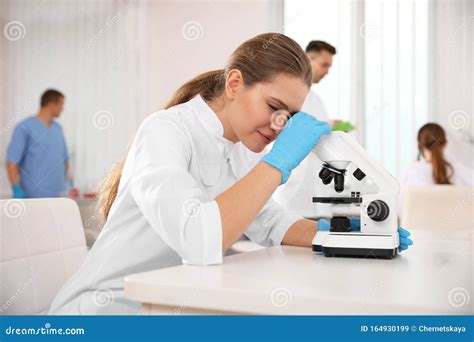 Scientist Using Microscope At Table And Colleagus Medical Research