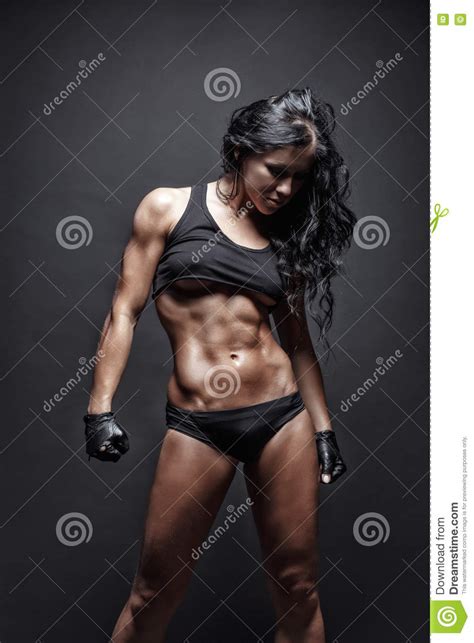 jeune fille musculeuse sexy de brune de forme physique posant au dessus du fond noir image stock