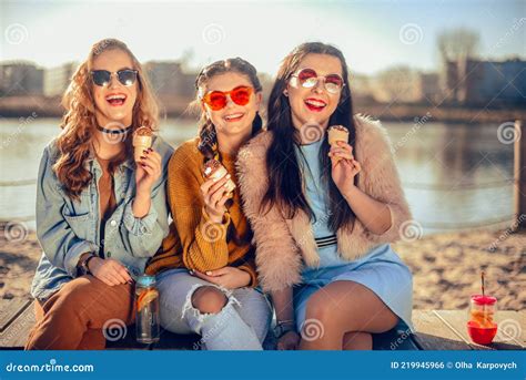 Three Girls Sit On The Beach Near The River Talk Gossip Joke Laugh Smile At Womans Day