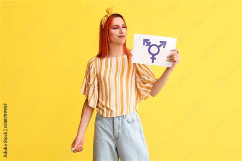 stylish transgender woman holding paper sheet with transgender symbol against yellow background
