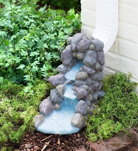 A Small Waterfall Made Out Of Rocks In The Ground Next To Some Plants