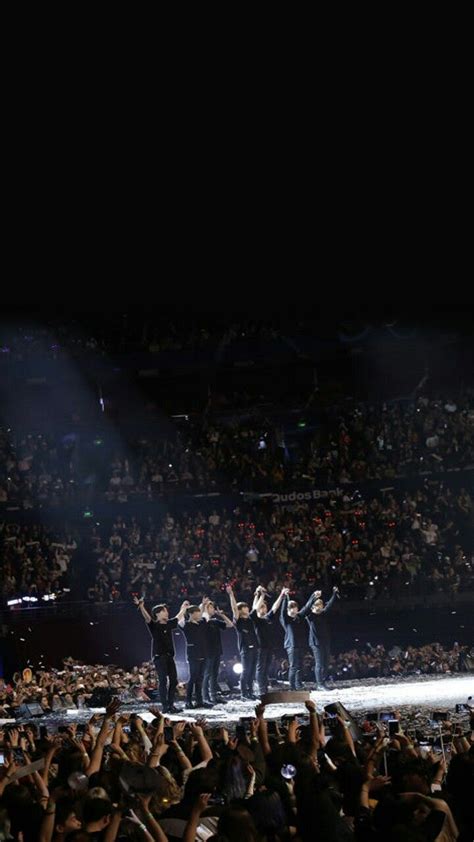 A Group Of People Standing On Top Of A Stage With Their Hands In The Air