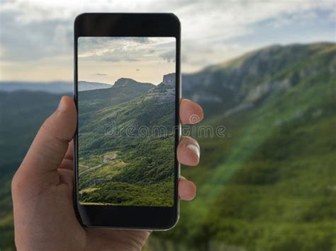 Hand Holding A Mobile Smartphone And Taking Landscape Photography Stock