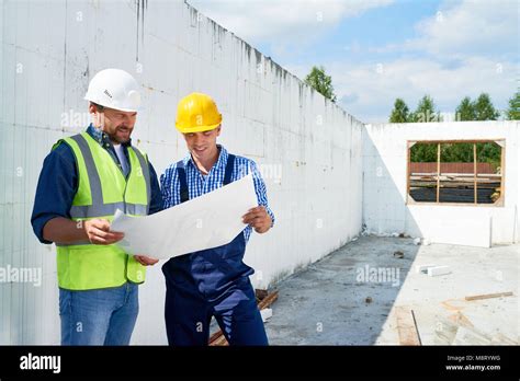 Construction Worker Discussing Floor Plans With Supervisor Stock Photo