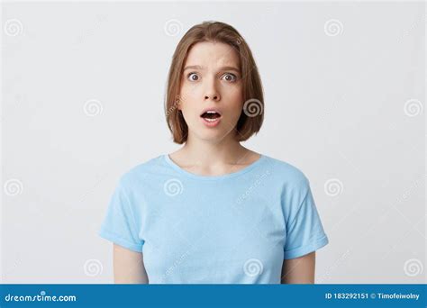 le portrait de la belle jeune femme stupéfaite dans la position bleue de t shirt avec la bouche
