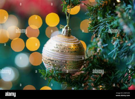 Shallow Focus Of A Golden Ornament On Holiday Tree With Blurred Bokeh