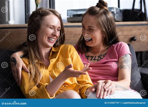 two pretty lesbians embracing while sitting on sofa in living room stock image image of