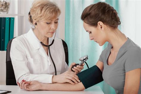 Doctor Measuring Blood Pressure Of Young Female Patient In Medical