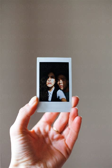 Female Hand Holding A Polaroid Photo Of A Man And Woman Hugged Porvertikala