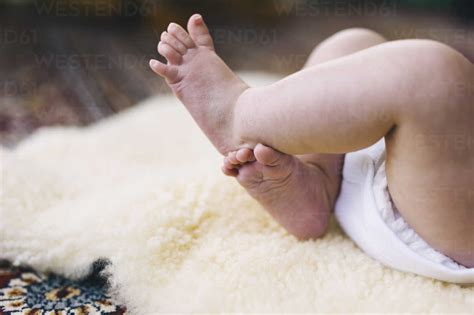 A Baby Lying On A Sheepskin Rug Kicking Her Legs Stock Photo