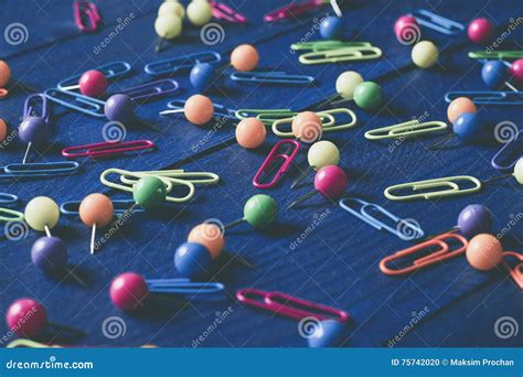 Background Of Scattered Colored Round Pins And Paper Clips On A Table