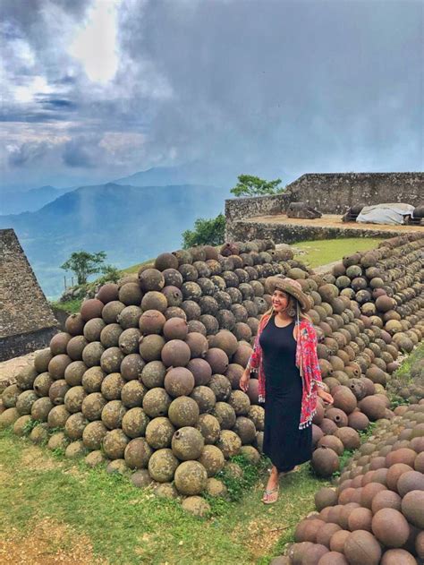 a woman standing in front of a pile of balls on the side of a hill