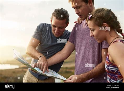 Blazing brave new trails together. three young hikers consulting a map