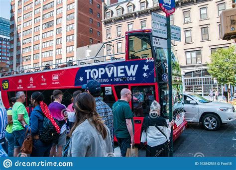 Tourists Lining Up To Board A Red Double Decker Sightseeing Bus In