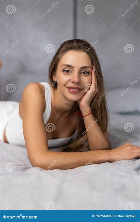 Smiling Brunette Woman Sitting On Bed At Home In Bedroom Stock Image