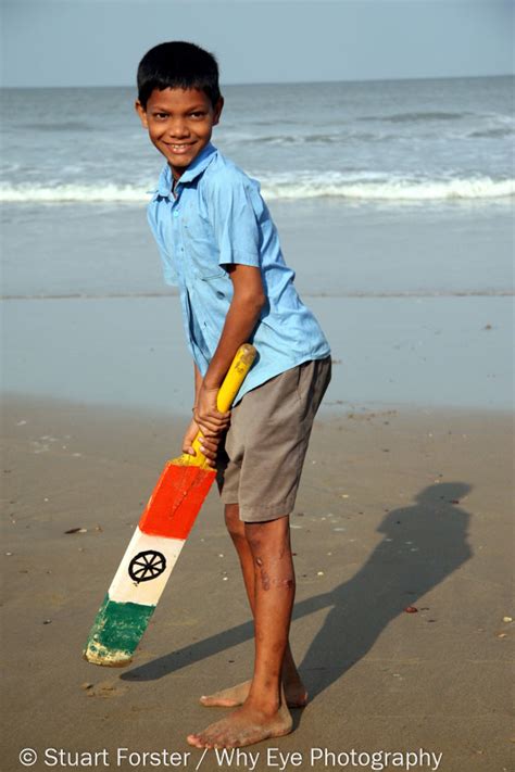 Indian Boy Playing Cricket On A Beach In With A Bat Bearing The Flag Of