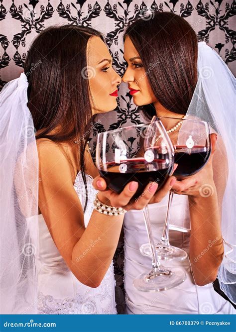 Pares Lésbicas No Vinho Tinto De Beijo E Bebendo Nupcial Do Vestido Do Casamento Imagem de Stock