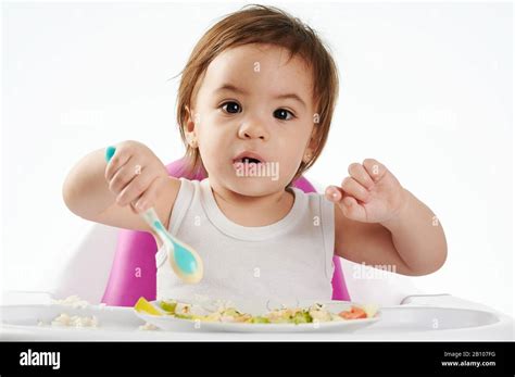 Cute Baby Eating Healthy Food On High Chair Isolated Stock Photo Alamy