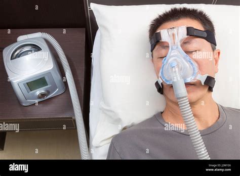 Asian Man With Sleep Apnea Using Cpap Machine Wearing Headgear Mask