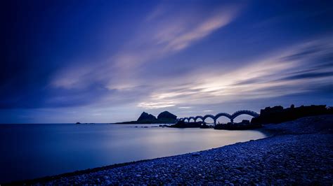 Sea Coast Stones Bridge Sunset Evening 4k Hd Wallpaper