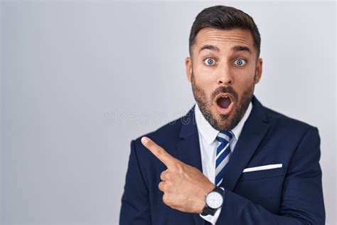 Handsome Hispanic Man Wearing Suit And Tie Surprised Pointing With Finger To The Side Open