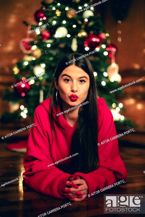 Portrait Of Teenage Girl Lying On The Floor In Front Of Christmas Tree Pouting Mouth Stock