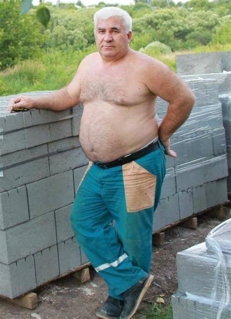 an older man standing next to a pile of cinder blocks with his hands on his hips