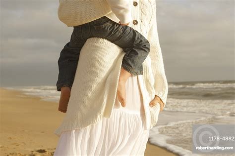 Mother Holding Child At Beach Stock Photo