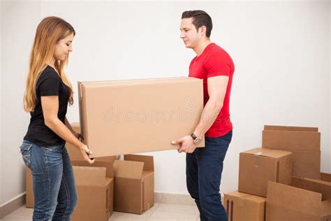 Couple Carrying Belongings In Moving Boxes In New Luxury House Stock