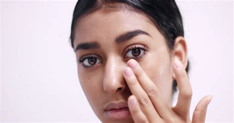 Applying eye cream in small dots under eyes and gently ...
