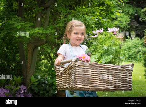Girl Gardening Carrying Flowers In Basket Stock Photo Alamy