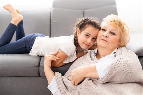 Happy Senior Grandmother Sit On Couch In Living Room Hugging Cute Little Preschooler