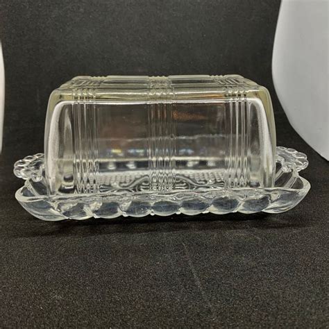 A Clear Glass Butter Dish Sitting On Top Of A Black Counter Next To A