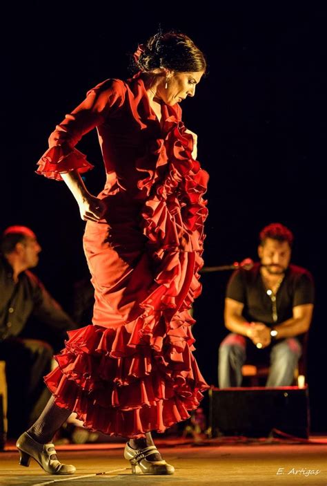 A Woman In A Red Dress Is Walking On The Stage With Other People Behind Her