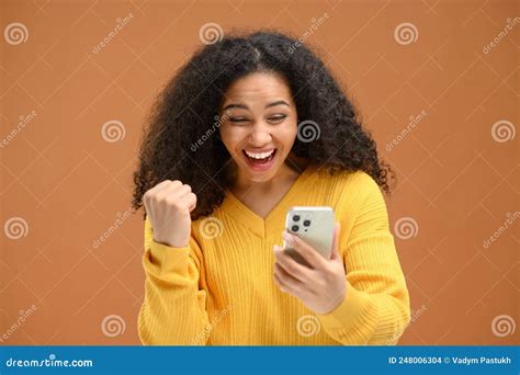 Young Shocked Woman Is Staring At Smartphone Screen Rejoicing With