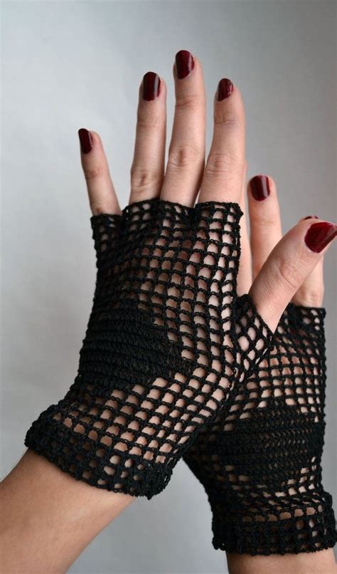 A Womans Hand With Red Nail Polish And Black Netted Gloves